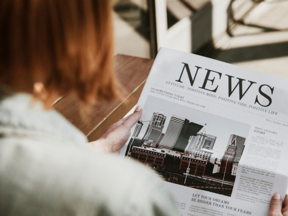 Eine Frau hält eine Zeitung mit Immobilien-News